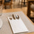 Guardanapo Kanguru 40x40 com talheres em mesa de restaurante — RAS Embalagens