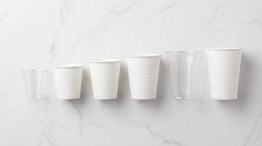 Copos descartáveis de plástico e papel para café e bebidas dispostos sobre superfície de mármore - RAS Embalagens