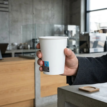 Copo de papel de 240ml com bebida quente segurado num café
