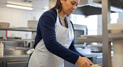 Profissional de catering com avental descartável branco a servir refeição — RAS Embalagens
